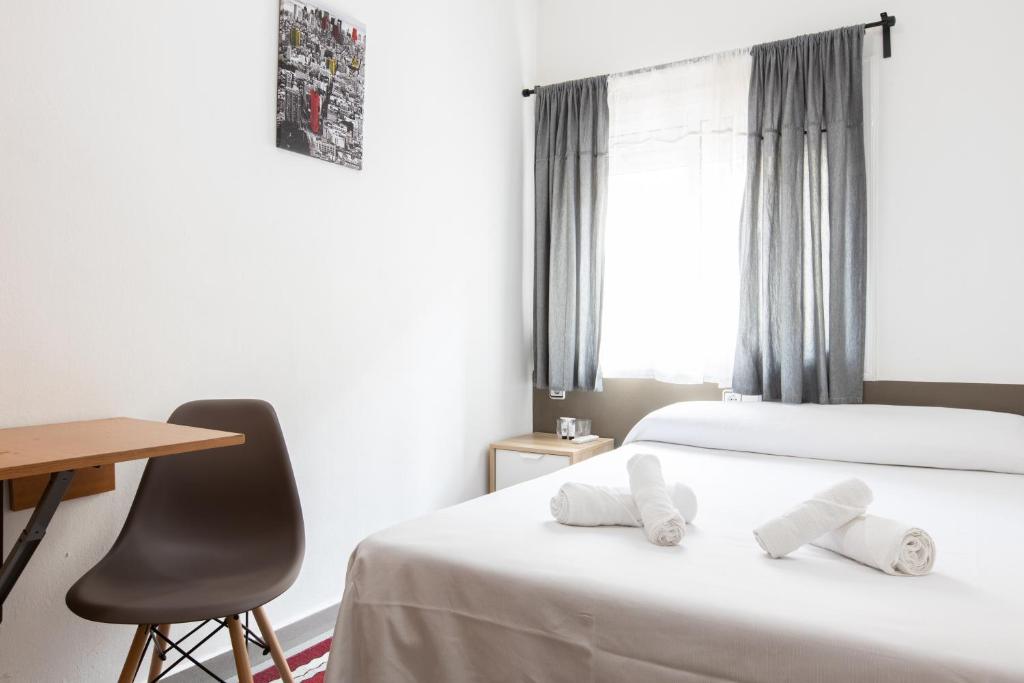 1 dormitorio con cama, escritorio y silla en Pensión Galicia en Canovellas
