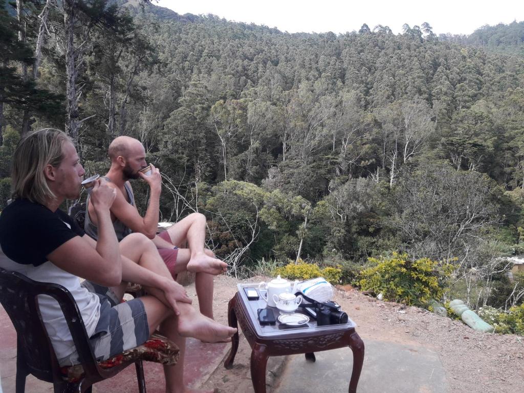 Dos personas sentadas en una mesa con vistas a un bosque en Ohiya Jungle resort en Ohiya