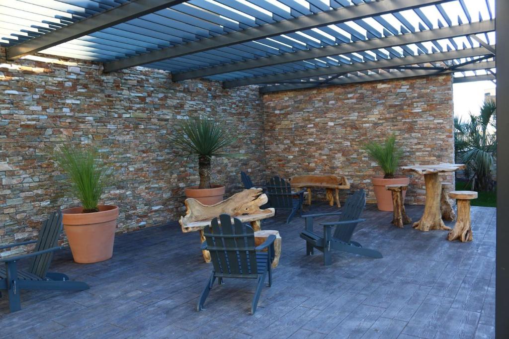 eine Terrasse mit Stühlen, Tischen und Ziegelwand in der Unterkunft APPT NEUF haut de gamme, Terrasse, Sud Montpellier in Pérols