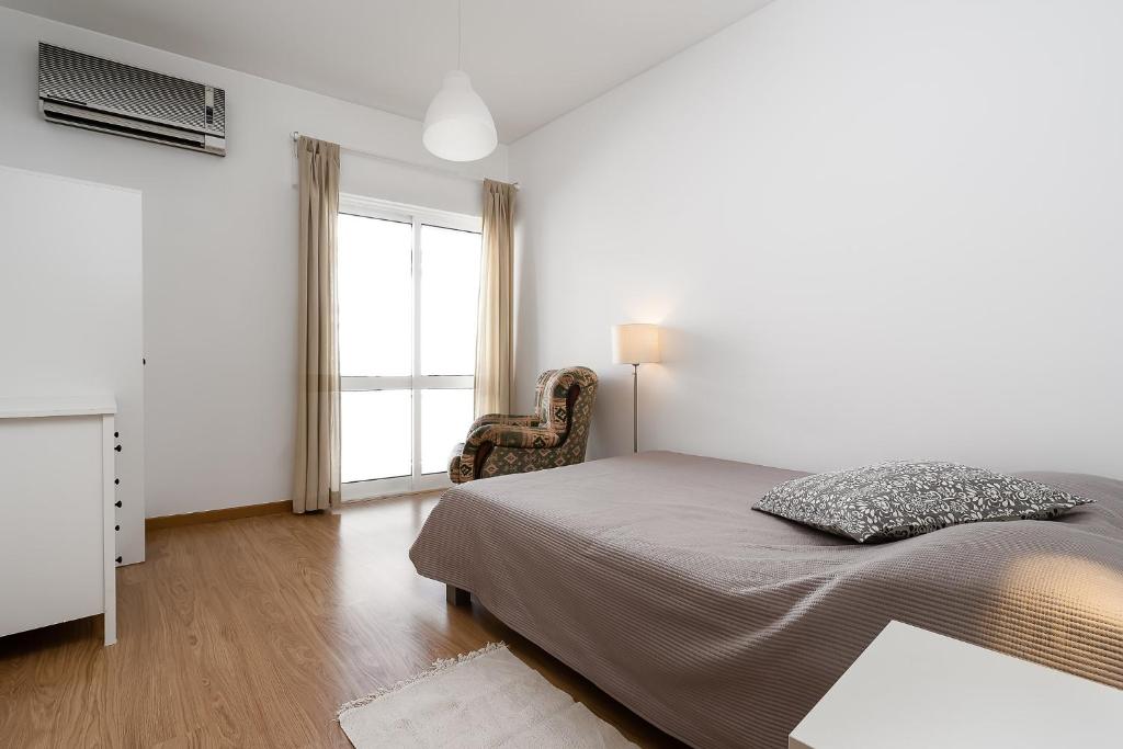 Un dormitorio con una cama y una silla y una ventana. en Casa Gago, en Faro
