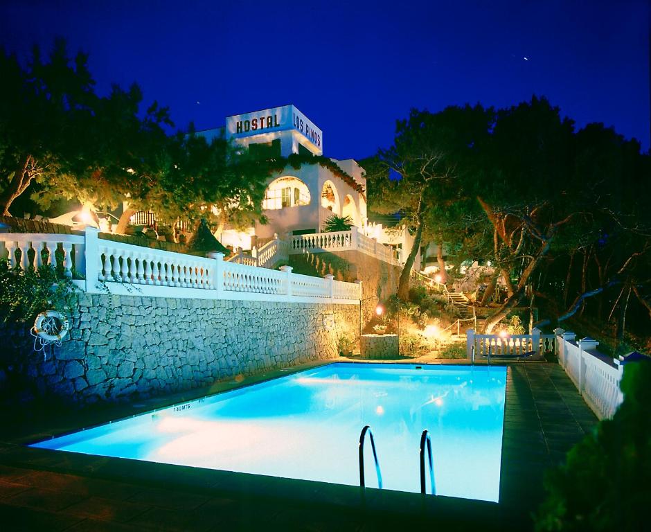 a swimming pool in front of a house at night at Hostal Los Pinos in Cala de Sant Vicent