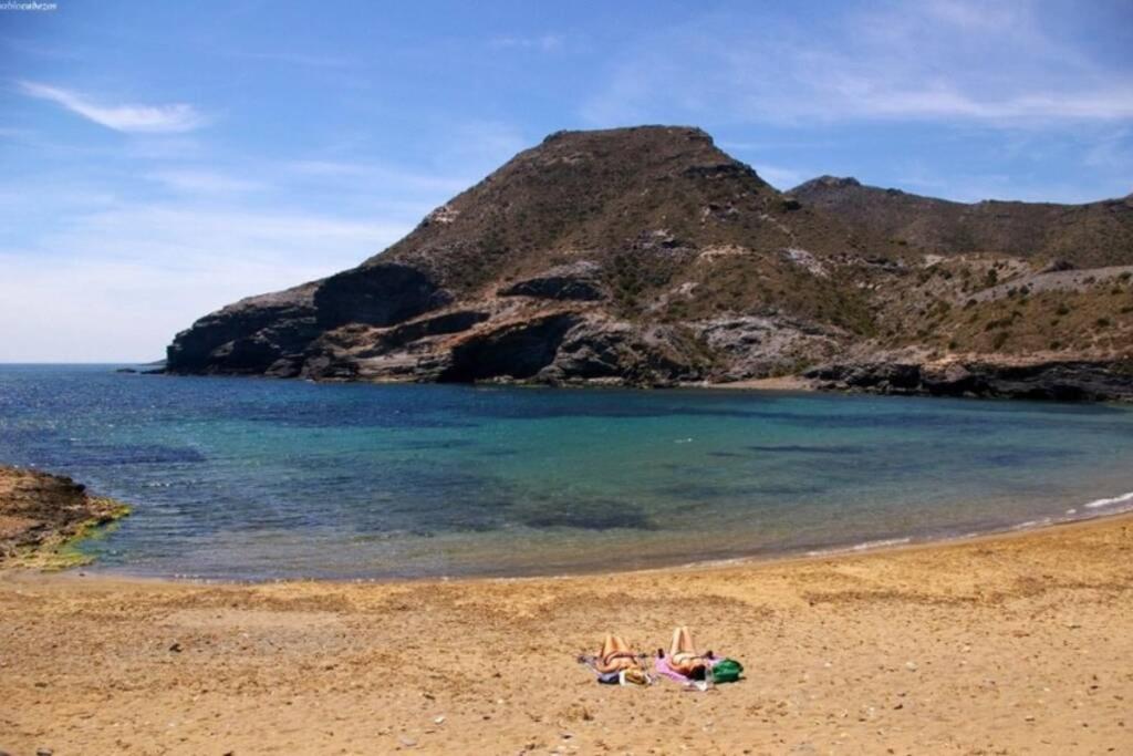a group of people laying on a beach near the water at The Beach Apartment - Sea views in Cabo de Palos