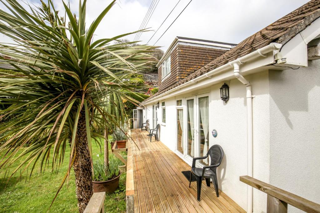 a wooden deck with a palm tree next to a house at Driftwood Spars in St. Agnes 