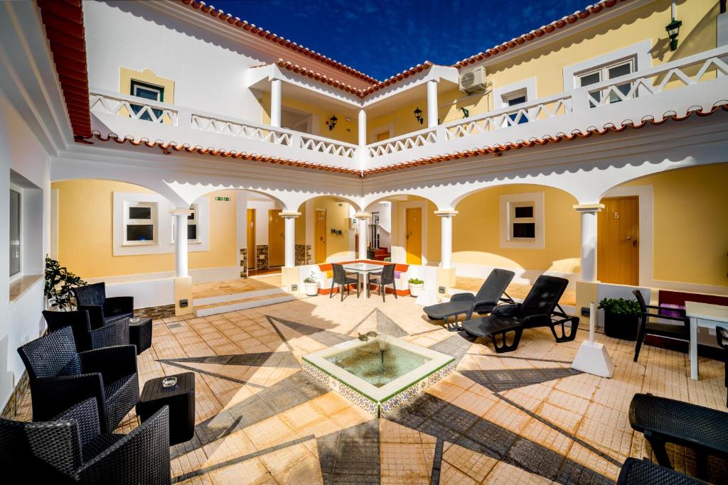 a courtyard in a house with chairs and a fountain at Rosa dos Ventos in Zambujeira do Mar