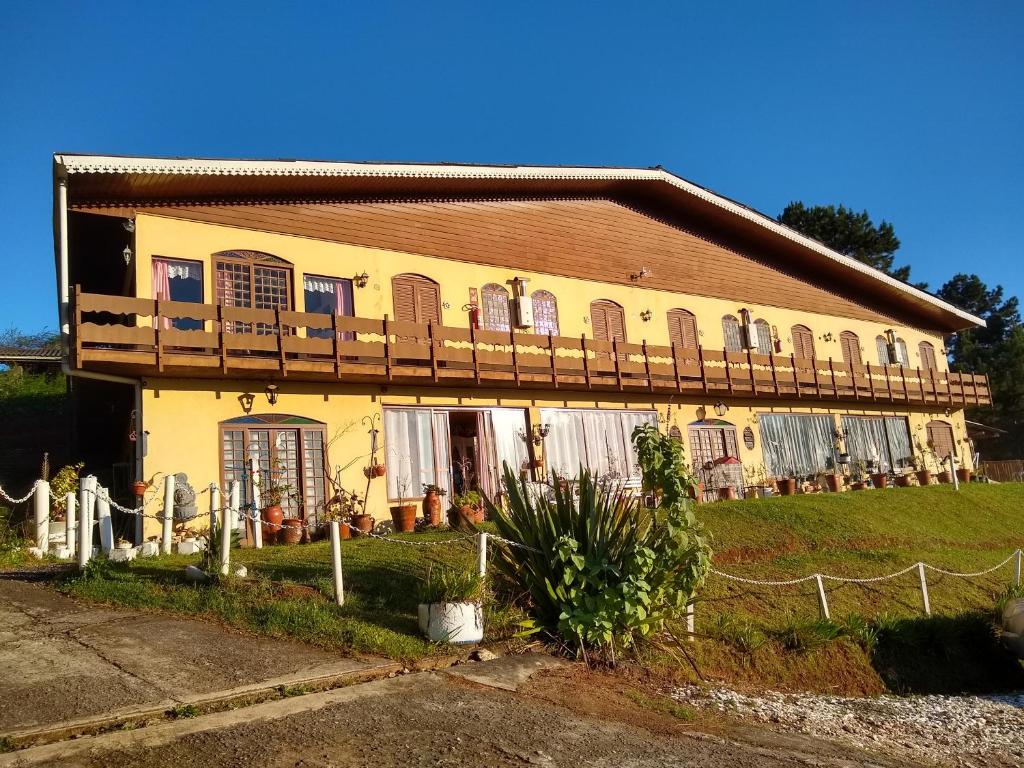 a yellow house with a balcony on top of it at Pousada Cachyto de Cielo in Campos do Jordão