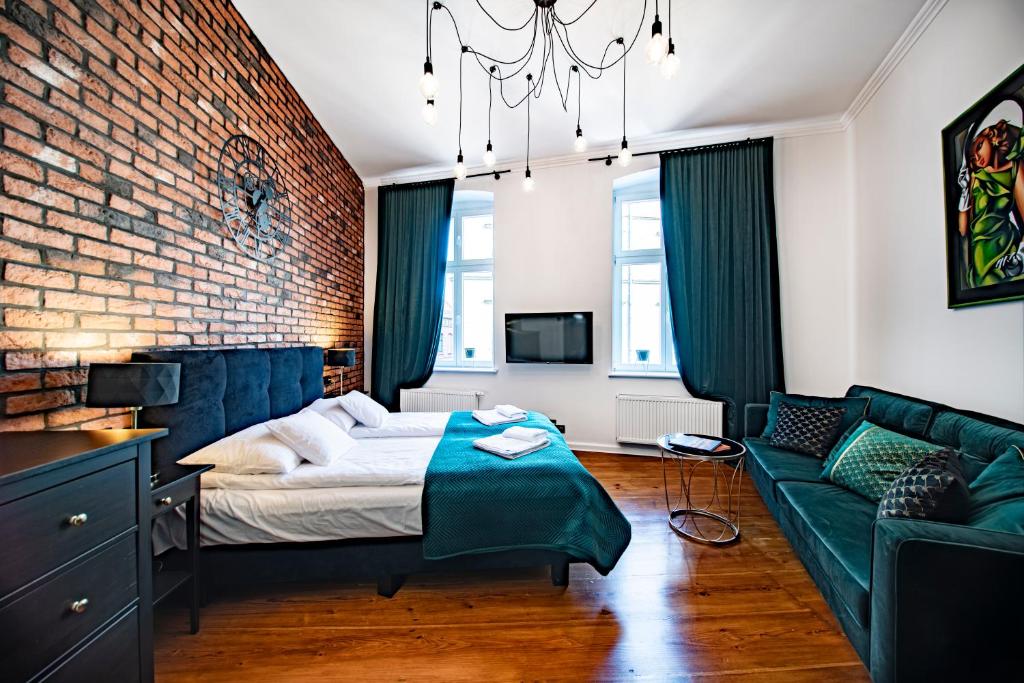 a bedroom with a bed and a brick wall at Apartamenty Dominikańskie 2 in Toruń