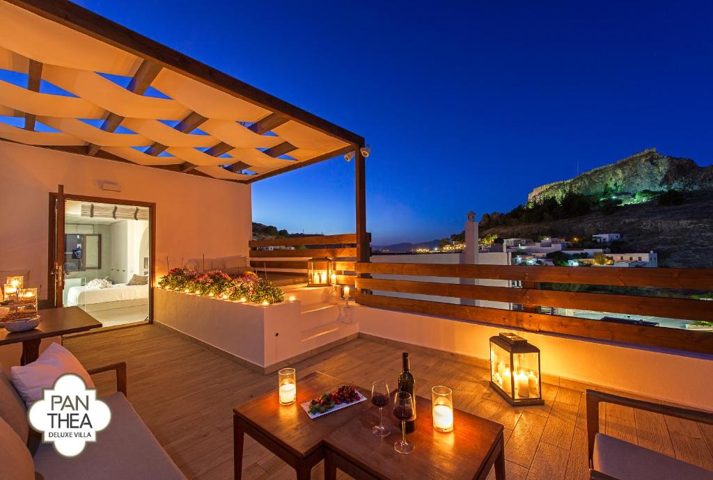 a rooftop deck with a view of the ocean at night at Villa Panthea in Líndos