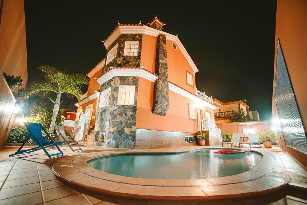 uma casa com piscina em frente a um edifício em Villa Morada Sonneland con piscina privada climatizada em Maspalomas