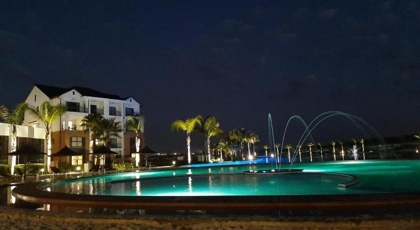 a large swimming pool with a fountain at night at The Blyde Crystal Lagoon One Bedroom Apartment in Pretoria