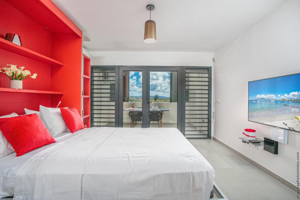 um quarto com uma grande cama branca com paredes vermelhas em STUDIO EQUIPE A L ETANG Z ABRICOTS em Fort-de-France