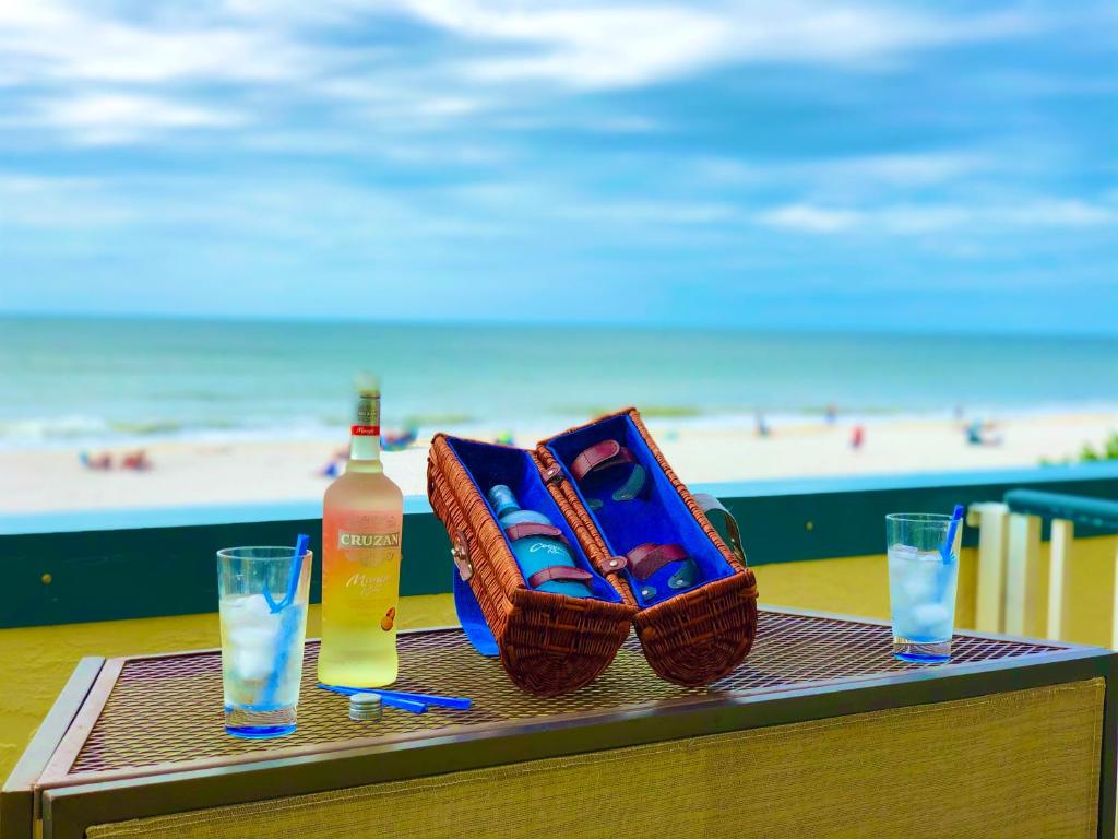 una mesa con una botella de bebida y una cesta en la playa en Soft, Sandy Beaches I Long Views from Premiere Over-sized Balcony!, en Marco Island