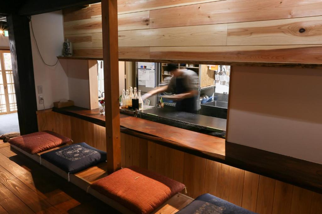 a man standing behind a bar in a kitchen at Guesthouse Izame Ann in Nagaoka
