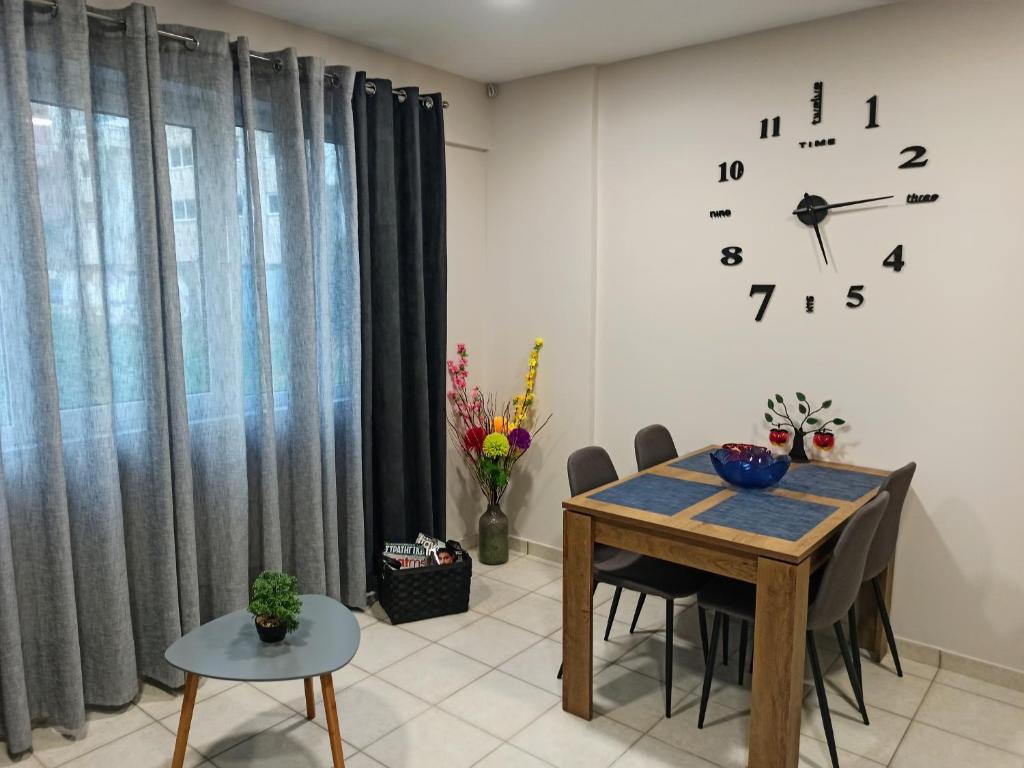 uma sala de jantar com uma mesa e um relógio na parede em Central Square Apartment 1 em Pirgos