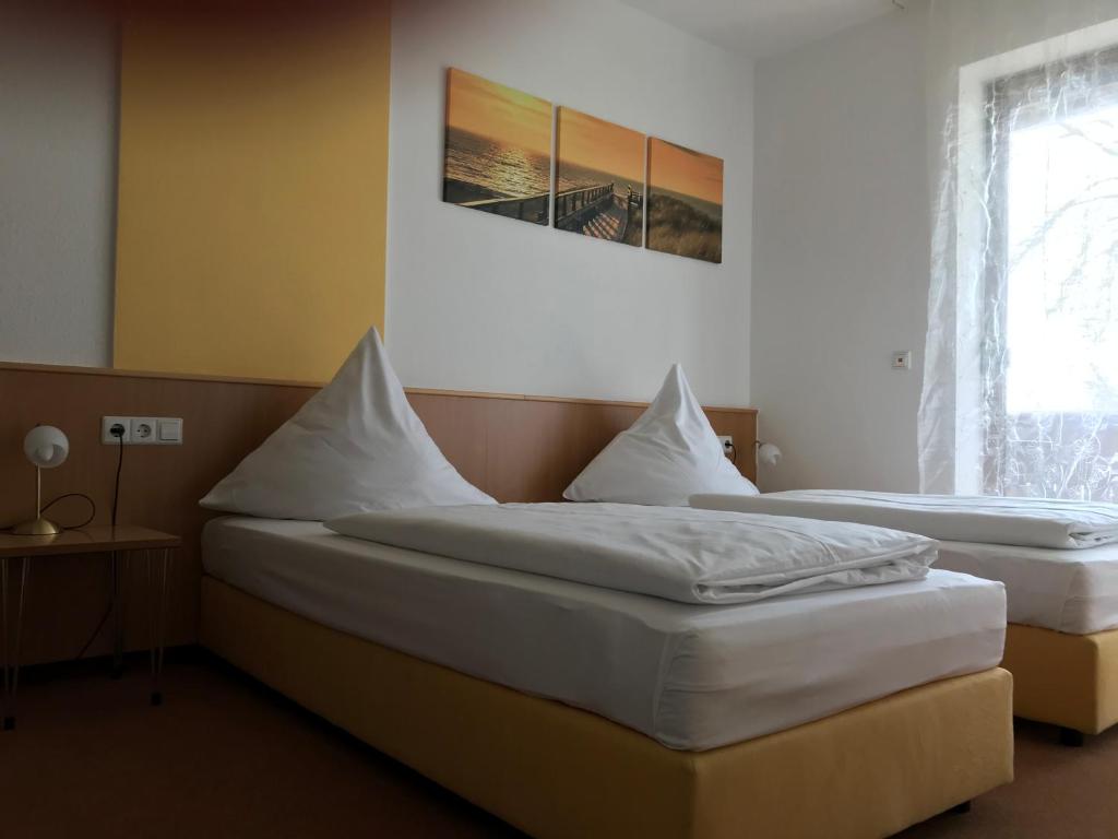 two twin beds in a room with a window at Landgasthof Felsenkeller in Dinkelsbühl