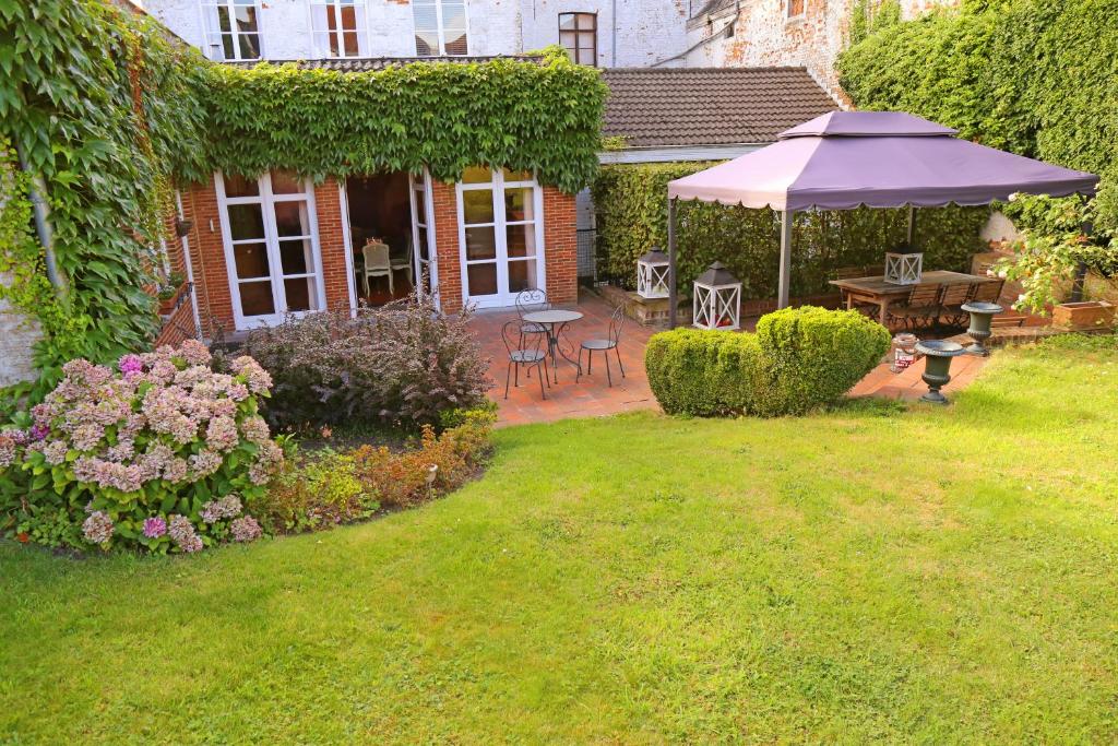 un jardín con mesa y sombrilla en Villa Theresa à 25 min de PAIRI DAIZA, en Soignies