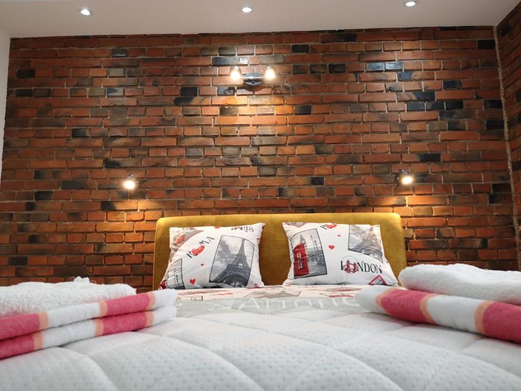 a bed in a room with a brick wall at Nikolic Apartment 2 in Leskovac