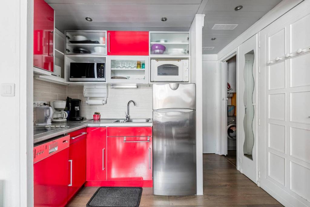 a kitchen with red cabinets and a stainless steel refrigerator at Twins 2 Alpes centre station in Mont-de-Lans