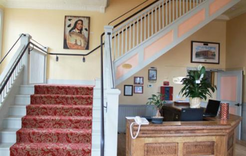 a lobby with a staircase with a red rug and a stair case at Windsor Hotel & Restaurant in Del Norte