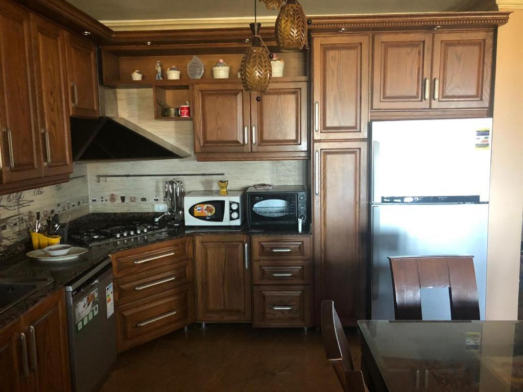 eine Küche mit Holzschränken und einem Kühlschrank in der Unterkunft Lazorde bay duplex chalet, North coast in El-Alamein