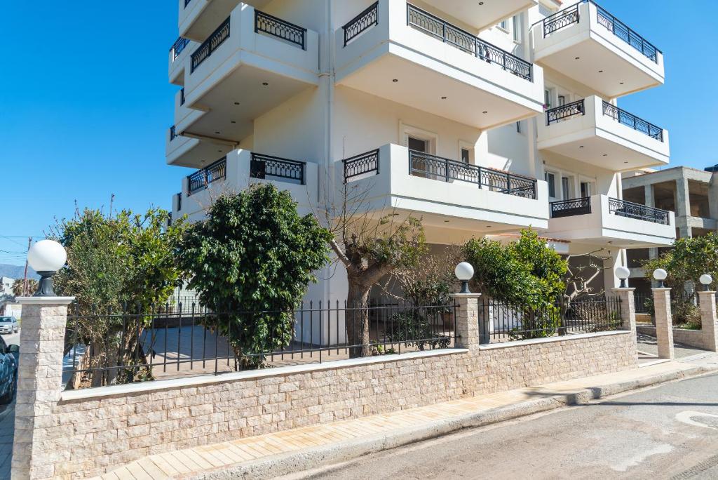 een groot wit gebouw met balkons aan een muur bij Bluewind Apartments - Near the Sea in Kissamos