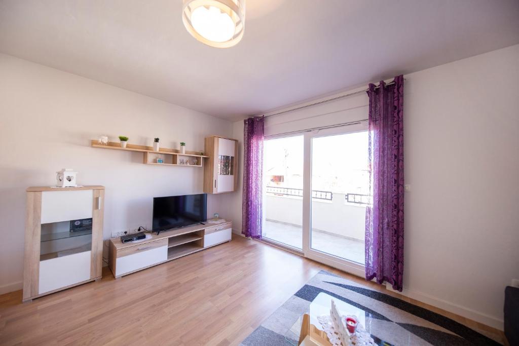 a living room with a television and a large window at Apartman 2 Relax Zadar in Zadar