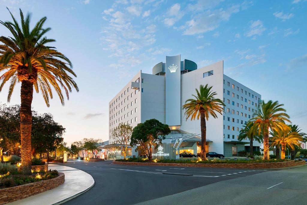 a building with palm trees in front of a street at Crown Promenade Perth in Perth