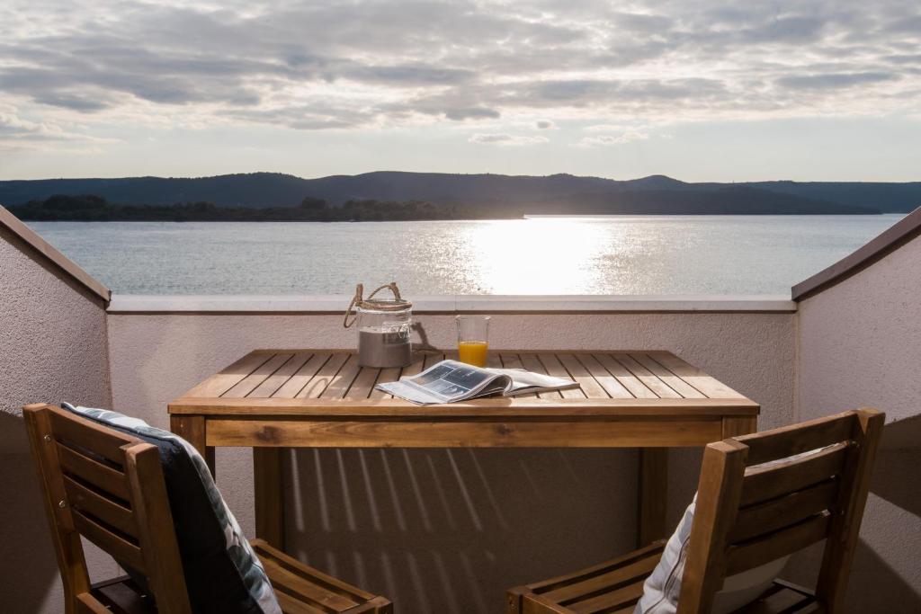 a table on a balcony with a view of the water at BonaMare Apartments in Turanj