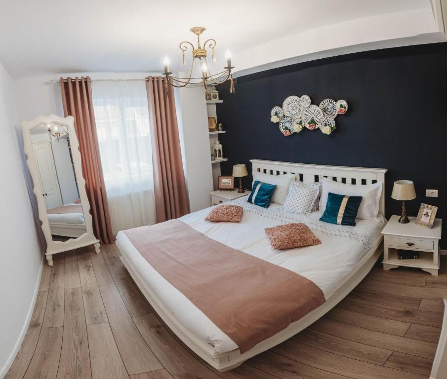 a bedroom with a large white bed with blue pillows at La Contessa Apartament in Tîrgu Neamţ