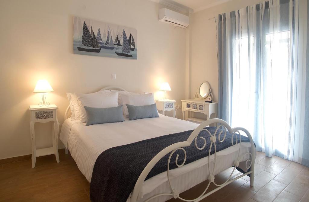 um quarto com uma cama com lençóis brancos e almofadas azuis em The Bluehouse - Spacious top floor flat with parking, by Mon Repos beach em Corfu Town