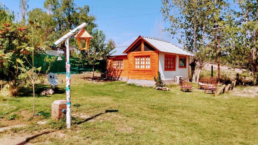 een kleine houten hut in een tuin met een huis bij Cabañas El Abuelo Alfredo in Ciudad Lujan de Cuyo