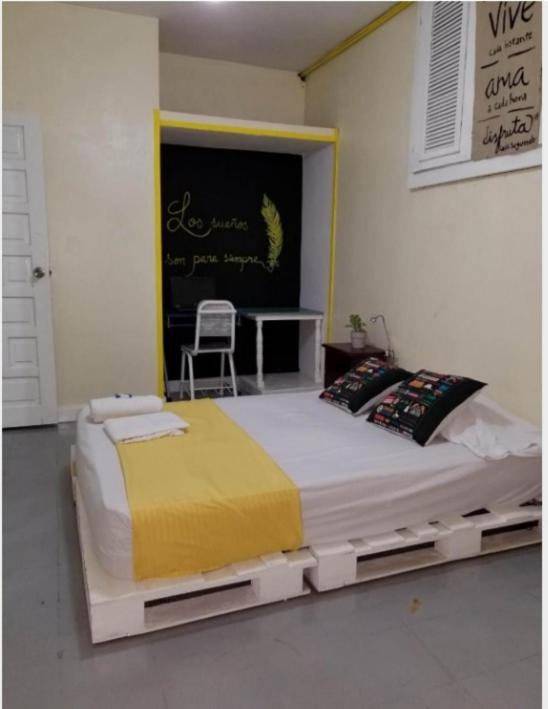 a large bed in a room with a table and a chair at Recycled house in Santo Domingo