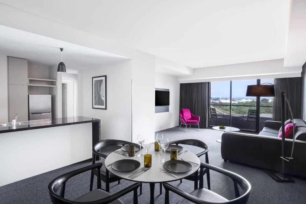 een woonkamer met een tafel en stoelen en een bank bij Mantra Southbank in Melbourne