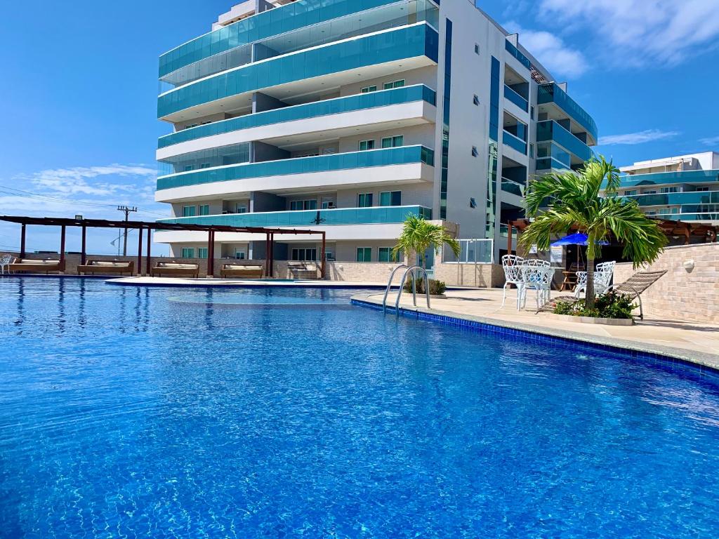 a large swimming pool in front of a building at Apartamento Le Bon Vivant Arraial do Cabo in Arraial do Cabo