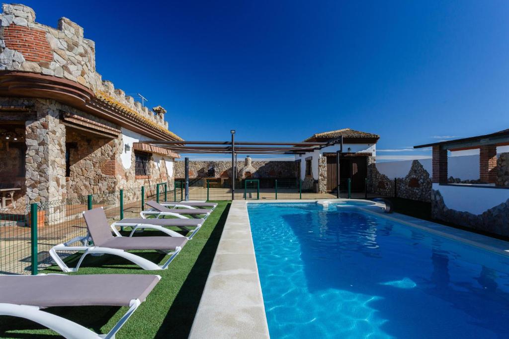 a swimming pool with lounge chairs next to a house at El Castillito in Chiclana de la Frontera