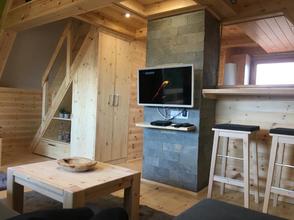 ein Wohnzimmer mit einem TV und einem Tisch in der Unterkunft Wooden Apartman Prémium Jacuzzival in Alsóörs