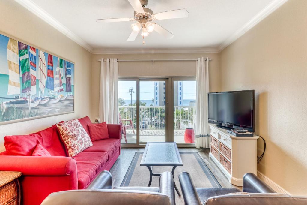 sala de estar con sofá rojo y TV de pantalla plana en Crystal Tower Condominiums en Gulf Shores
