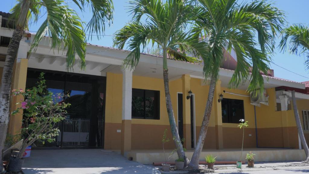 a yellow house with palm trees in front of it at RQ Cozy Two Bedroom House in General Santos