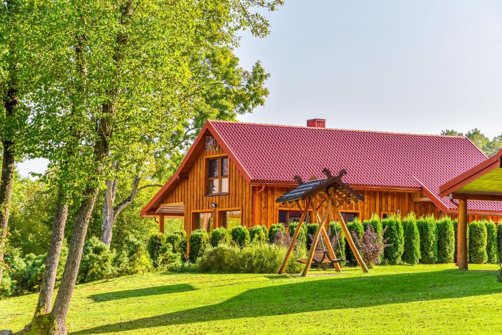 a wooden house with a yard in front of it at Vila LATO in Latežeris