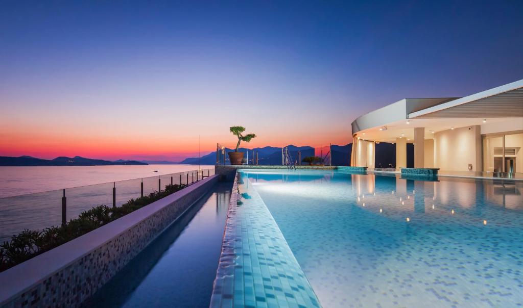 a large swimming pool next to a building with the ocean at Royal Blue Hotel in Dubrovnik