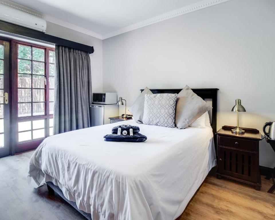 1 dormitorio con 1 cama grande con sábanas blancas en The Nightingale Guesthouse, en Bloemfontein