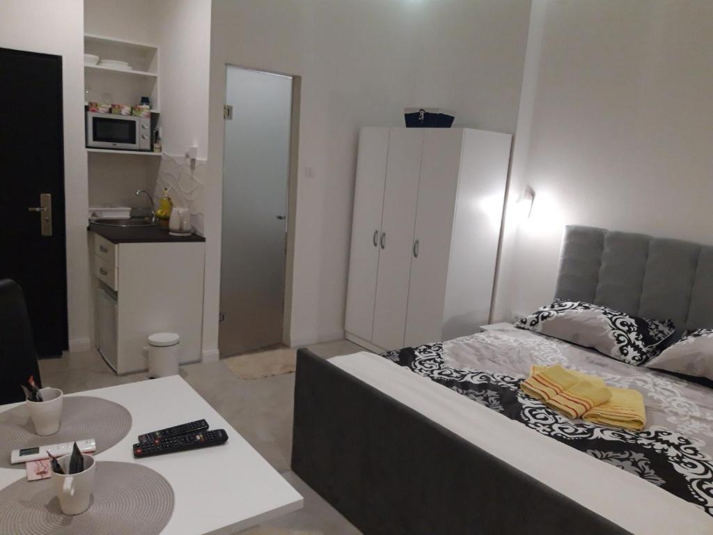 Un dormitorio con una cama y una mesa y una cocina. en Apartmani Krtolica, en Novi Sad
