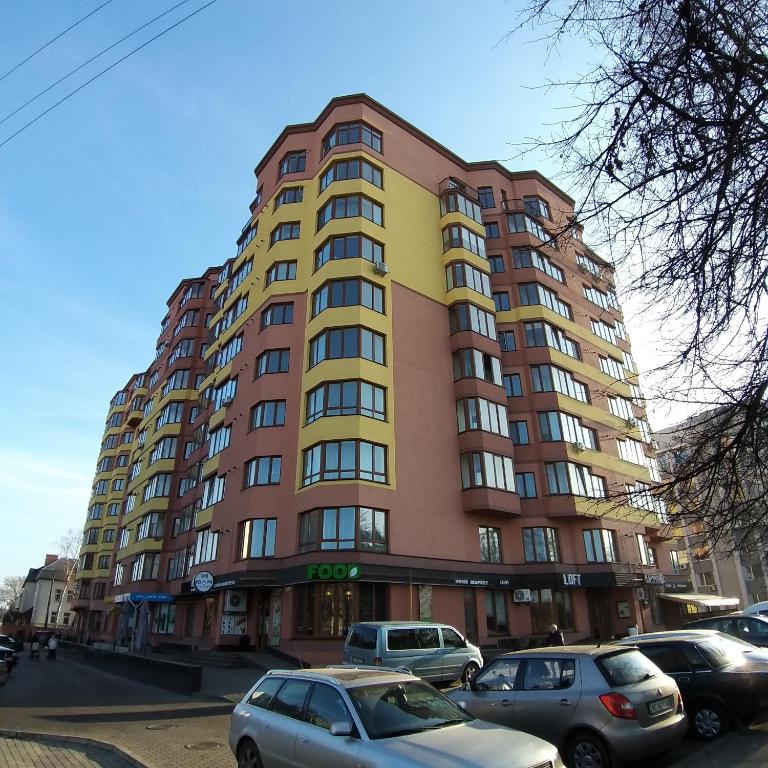a tall building with cars parked in front of it at Квартира-студія центр Огієнка 2а in Lutsk