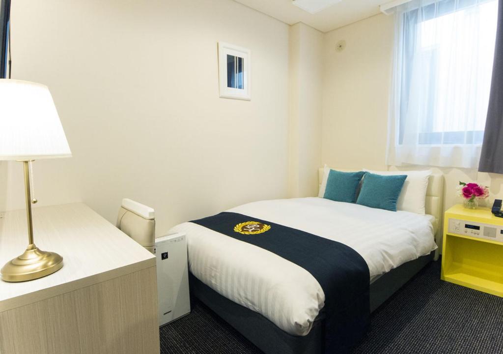a bedroom with a bed and a lamp and a window at Grand Park Hotel Panex Tokyo in Tokyo