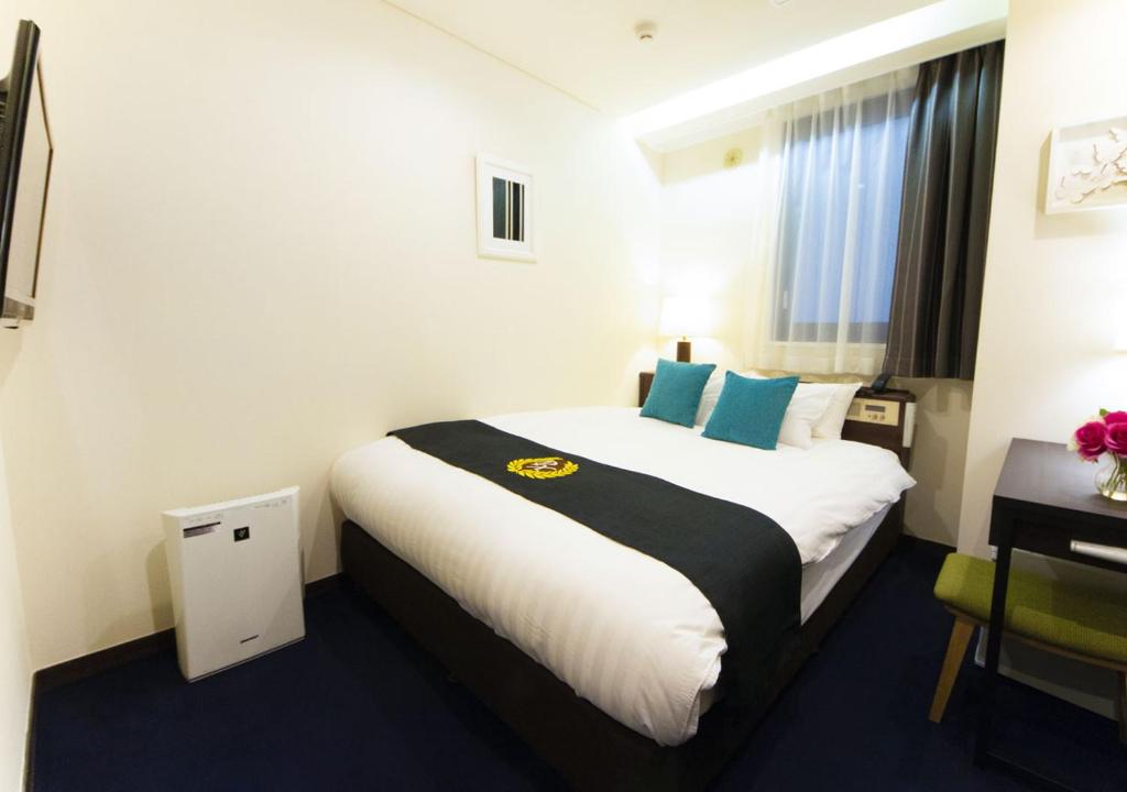 a hotel room with a bed and a desk at Grand Park Hotel Panex Tokyo in Tokyo