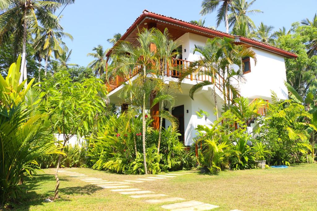 a white house with palm trees in front of it at ANB Surf View in Tangalle