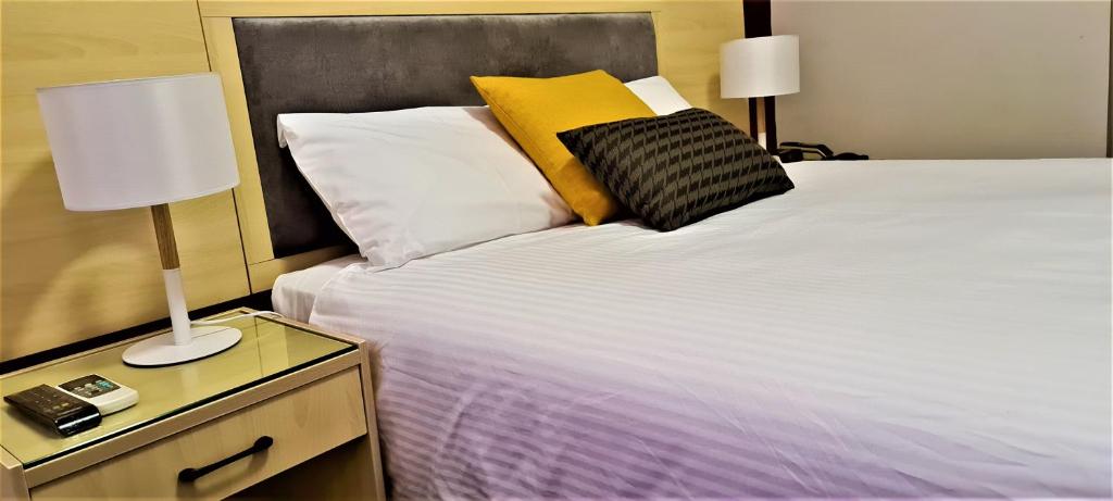 a bedroom with a large bed with a night stand with a lamp at Brunswick Tower Hotel in Melbourne