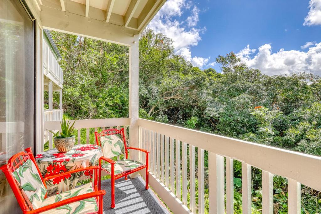a porch with two red chairs and a table at Hale Moi 102B in Princeville