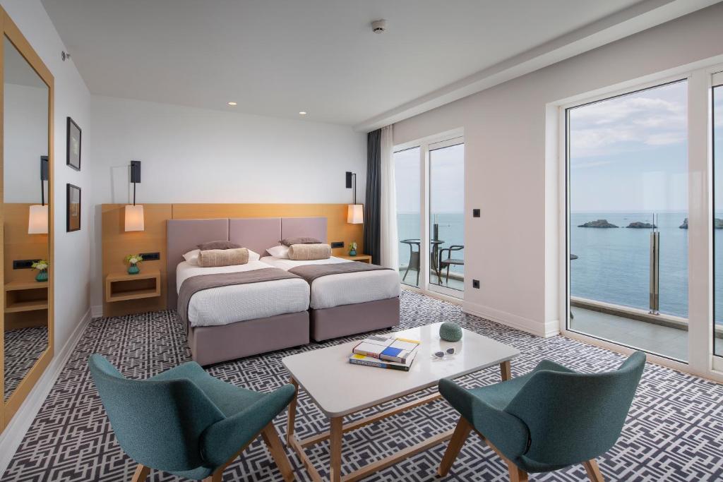 a bedroom with a bed and a table and chairs at Royal Neptun Hotel in Dubrovnik