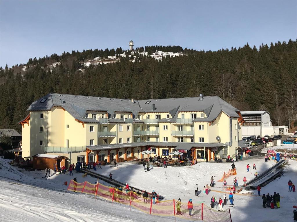 ein großes Gebäude mit einem Haufen Leute im Schnee in der Unterkunft Ferienwohnung Gipfelstürmer Feldberg - Ski in Ski out, Whirlpool & Infrarotkabine in Feldberg