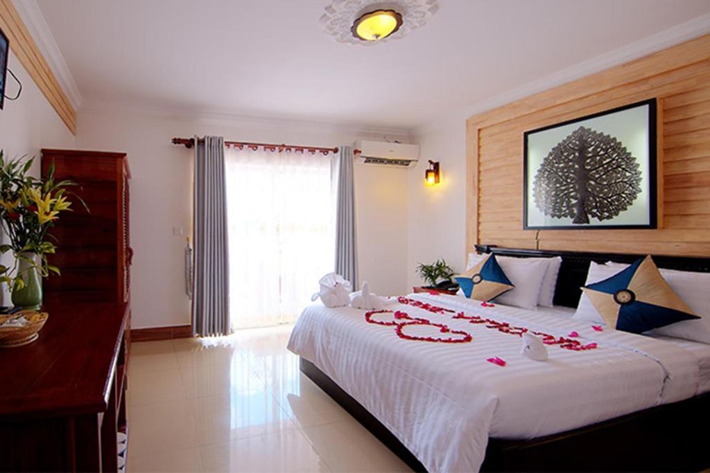 um quarto com uma grande cama branca com decorações vermelhas em Bou Phanith Villa em Siem Reap